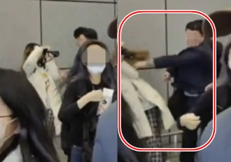 A bodyguard for BoyNextDoor pushes a fan at Qingdao Jiaodong International Airport in China on Saturday. [SCREEN CAPTURE]