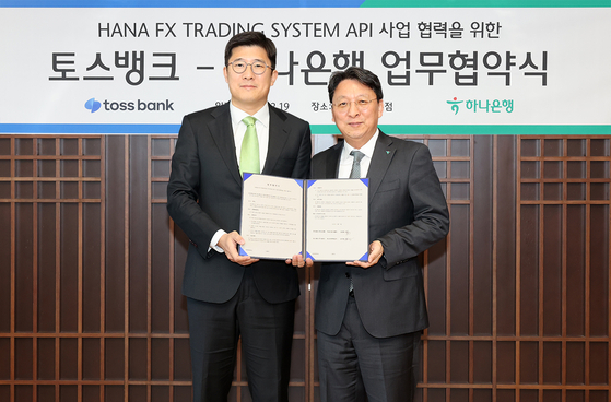 Nam Goong-won, Deputy President of Hana Bank's Financial Markets Group, right, and Kim Jee-woong, Chief Strategy Officer at Toss Bank, pose for a photo following a partnership on foreign exchange service at Hana Bank headquarters in central Seoul on Tuesday. [HANA BANK]