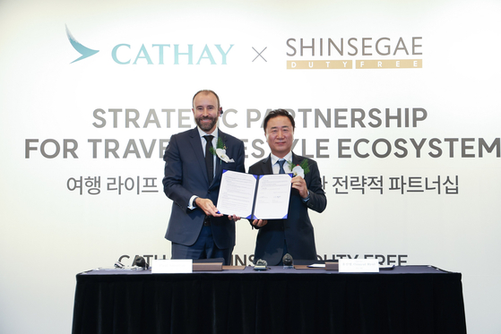 Ryu Sin-yul, CEO of Shinsegae DF, right, and Paul Smitton, Asia Miles CEO at Cathay Pacific, sign a business agreement at the Westin Chosun Hotel during a event titled "Strategic Partnership for Travel Lifestyle Ecosystem." [SHINSEGAE DF]