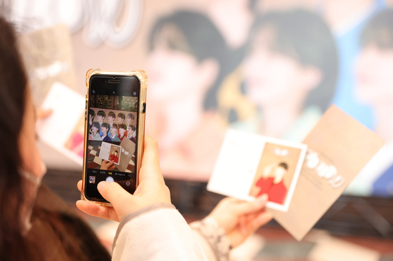 A woman takes a picture of Seventeen's photo cards [HYBE JAPAN]