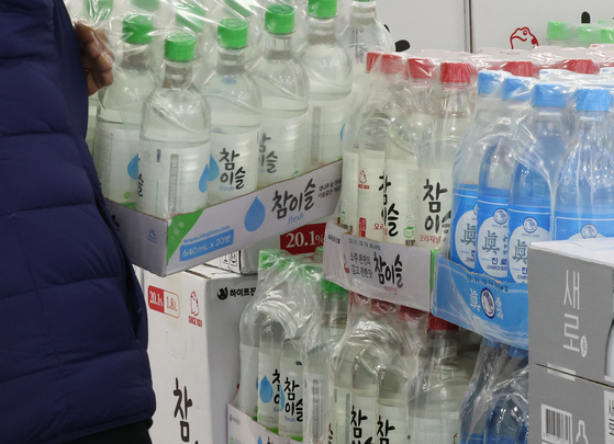 Hite Jinro's soju bottles are stacked at a discount mart in Seoul on Thursday. The liquor company said that day that it will slash its soju wholesale prices by 10.6 percent on Friday, earlier than the previously announced date of Jan. 1, to lessen the burden on consumers and small businesses. [NEWS1]