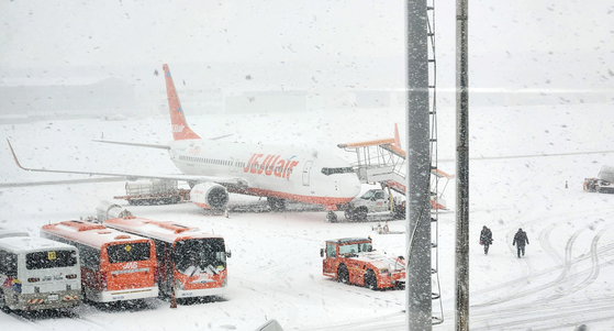 Flights were canceled or delayed at Jeju International on Friday morning due to heavy snow that hit the island. Pictured is a parked aircraft at the airport on Friday. [YONHAP] 