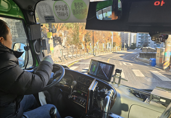 A village bus driver drives through an area in Seongdong District, eastern Seoul, recently installed with under-road heating system on Dec. 21. [LEE YOUNG-KEUN] 