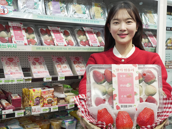 A model poses with a "Strawberry Sampler" that includes three types of homegrown strawberries sourced from South Jeolla and South Chungcheong. Convenience store chain 7-Eleven, which recently started selling the packages, has been keen on strawberry sales since 2021 when purchases of King's Berry from Nonsan, South Chungcheong, boosted the franchise's strawberry sales by threefold compared to the previous year. [7-ELEVEN]