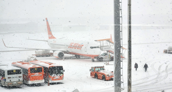 Flights were canceled or delayed at Jeju International on Friday morning due to heavy snow that hit the island. Pictured is a parked aircraft at the airport on Friday. [YONHAP]
