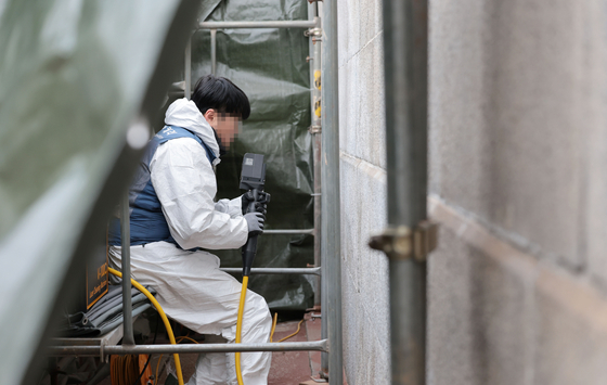 Cultural Heritage Administration official works on the restoration of the vandalized Gyeongbok Palace wall on Dec. 19. [YONHAP]