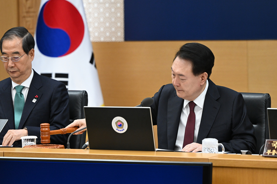 President Yoon Suk Yeol, right, bangs the gavel to start his last Cabinet meeting of the year at the Sejong government complex on Tuesday. [PRESIDENTIAL OFFICE]