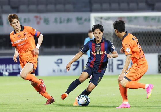 Suwon FC's Lee Seung-woo, center, dribbles the ball during a K League match against Gangwon FC at Suwon Sports Complex in Suwon, Gyeonggi on June 25. [YONHAP] 