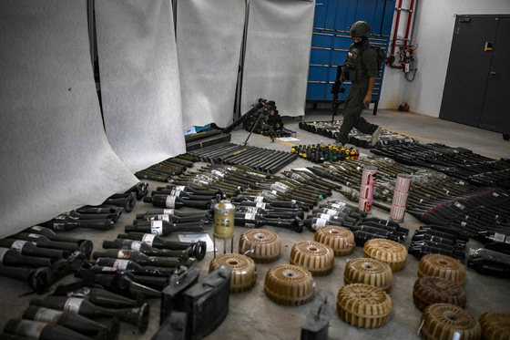 An Israeli soldier walks near armaments during an official media tour organized by the Israeli military on Oct. 26, where it displayed a variety of weapons recovered from areas hit by the Palestinian Hamas militants during their Oct. 7 attack on communities across southern Israel. Israel's military on Oct. 26 said a portion of the weapons used by Hamas during the militant group's Oct. 7 attacks were made in Iran and North Korea. [AFP/YONHAP]