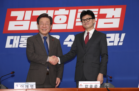 From left, Democratic Party leader Lee Jae-myung and People Power Party interim leader Han Dong-hoon shakes hands before a meeting at the DP's National Assembly office in Yeouido, Seoul, on Friday. [YONHAP]