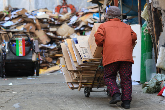 An old woman tows scraps of paper she picked up in the streets to a scrap shop in Jongno District, central Seoul, to sell them at some 70 won ($0.05) per kilogram on Thursday. [YONHAP]