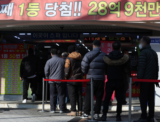 People stand in a line to buy lottery tickets in Nowon District, northern Seoul, on Monday. [YONHAP] 