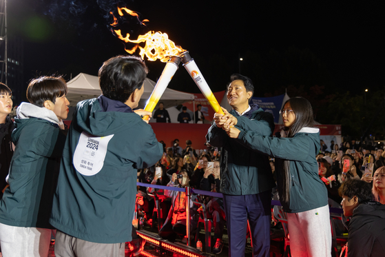 The Olympic flame is passed from one torch to the next during a ceremony to mark the start of the 2024 Gangwon Youth Olympics torch relay at Seoul Plaza in central Seoul on Wednesday.  [GANGWON YOUTH OLYMPICS ORGANIZING COMMITTEE]