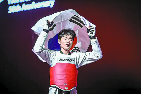 Taekwondo practitioner Bae Jun-seo celebrates with the Korean flag after beating Georgi Gurtsiev 2-0 in the flyweight final of the 2023 World Taekwondo Championships at Baku Crystal Hall in Baku, Azerbaijan on Tuesday. Bae's gold medal is Korea's first in this year's tournament and his first since the 2019 World Championships. [YONHAP]