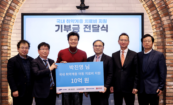 Park Jin-young poses for photos with the officials from the hospitals, at the donation presentation ceremony held at JYP Entertainment headquarters in Gangdong District, eastern Seoul on Tuesday. [JYP ENTERTAINMENT]