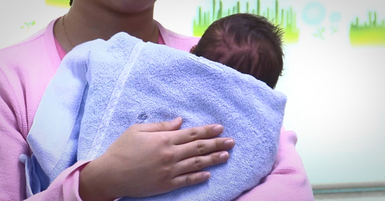 A nurse holds a newborn at a hospital in Seoul [YONHAP]