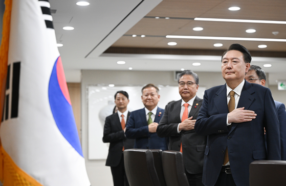 President Yoon Suk Yeol, right, salutes the flag at his first Cabinet meeting of the New Year at the Yongsan presidential office in central Seoul on Tuesday, joined by his ministers. [JOINT PRESS CORPS]