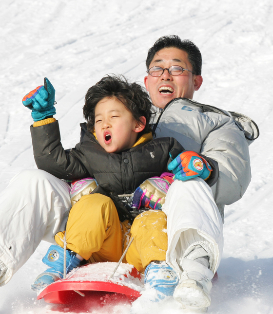 Visitors at Seoulland in Gwacheon, Gyeonggi, enjoy sledding down a slope at the theme park. [LIM HYUN-DONG]