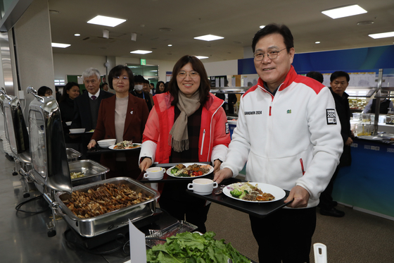 From right: Co-head of the Gangwon 2024 Winter Youth Olympics Organizing Committee Choi Jong-ku; Second Vice Minister of Sports Jang Mi-ran and Vice Minister of Food and Drug Safety Kim Yoo-mi wait in line at the Gangneung-Wonju National University cafeteria in Gangneung, Gangwon on Wednesday to eat a sample of the food that will be served to athletes during the Gangwon Youth Olympics set to begin on Jan. 19. [PARK SANG-MOON]