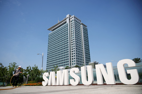 A worker waters a flower bed beside the logo of Samsung Electronics at the company's headquarters in Suwon, Gyeonggi. [REUTERS]