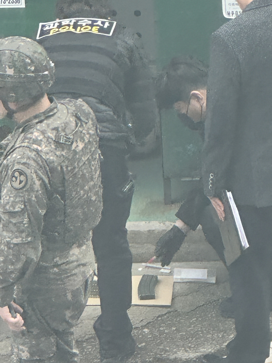 Police and the military investigate a magazine and blank bullets found in a clothing collection box at a Gimhae apartment complex in South Gyeongsang on Wednesday. The police were alerted to the discovery at 9:55 a.m. However, no additional items, such as a rifle, have been located thus far. The case is currently under investigation by both the police and the 39th Infantry Division. [YONHAP]