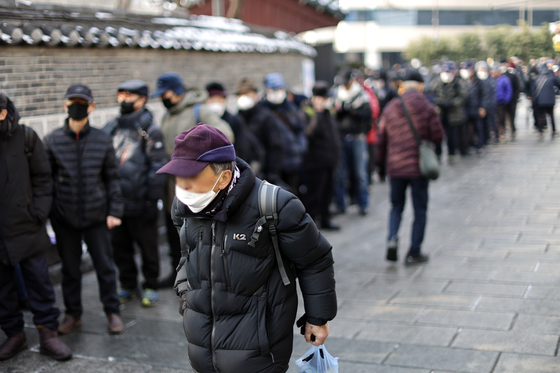 Elderly people line up at the soup kitchen located in Tapgol Park, Jongno District, on Wednesday. [YONHAP]  
