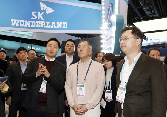 Hyundai Motor Group Executive Chair Euisun Chung, at the center, and SK On's Executive Vice Chairman Chey Jae-won listens to explanation from the spokesperson at SK Group's booth for CES 2024 in Las Vegas on Tuesday. [SK ON] 