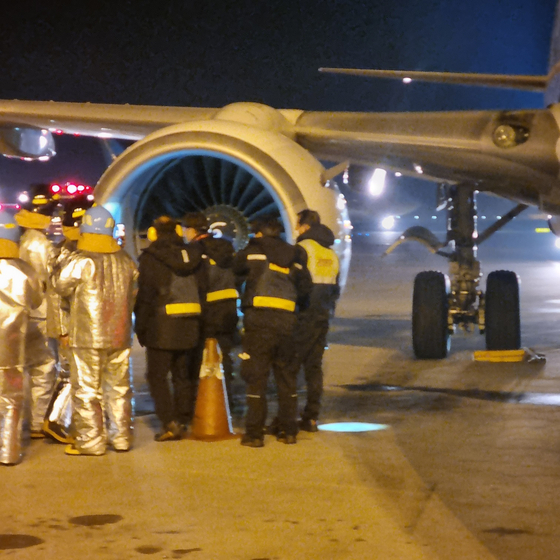 Firefighters and airport officials inspects the engine of a T’way flight that was struck by a bird on Wednesday. The flight that was traveling from Tokyo, however, landed safely on the runway. [YONHAP]
