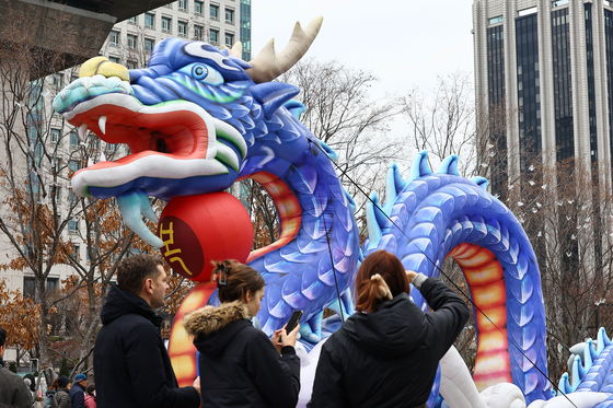 People take photos in front of the Blue Dragon statue at Gwanghwamun Plaza in central Seoul on Jan.1. According to the lunar calendar, year 2024 is the year of Blue Dragon. [JOONGANG PHOTO]