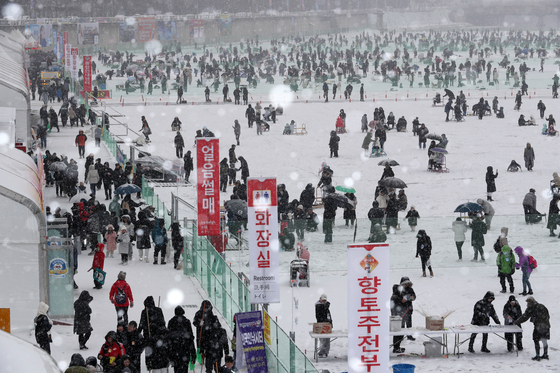 Snow falls on visitors ice fishing on a frozen river during the ongoing annual Hwacheon Sancheoneo Ice Festival in Hwacheon County in Gangwon on Sunday. The wintertime festival, first launched in 2003, usually attracts more than one million people annually, and the county said that the cumulative visitors this year has surpassed 500,000 so far. The 23-day event is set to run through Jan. 28 and involves activities including bare-hand fishing, sledding and ice football. Sancheoneo is a Korean freshwater mountain trout. [YONHAP] 