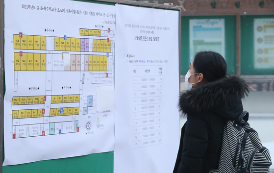 A test-taker and aspiring teacher looks at the seat map attached to the board for the second round of the city’s elementary teacher employment examination at Seoul Technical High School in Seoul on Jan. 13, 2021. [NEWS1] 