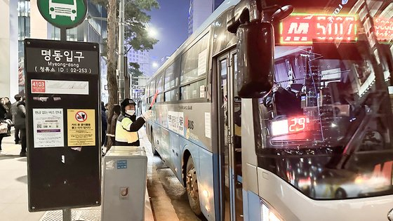 A traffic controller guides intercity buses stopping at the busy bus stop in Myeong-dong, downtown Seoul, located across from Lotte Young Plaza, at around 7 p.m. Wednesday. [MOON HEE-CHUL]