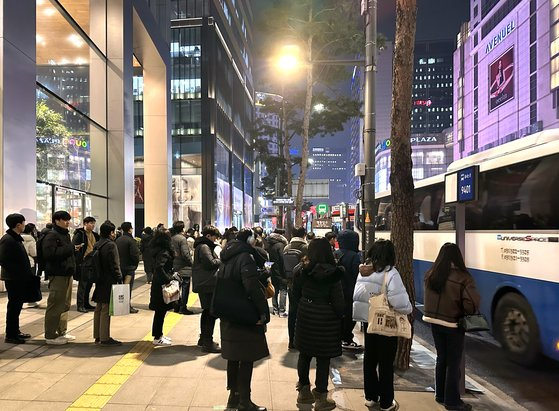 Commuters wait for their buses after work in Myeong-dong, downtown Seoul on Wednesday. [MOON HEE-CHUL]