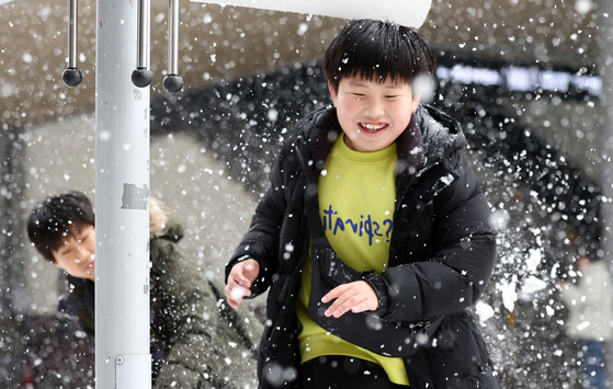 Children frolic in the snow in front of Seoul Station in central Seoul on Wednesday afternoon amid heavy snowfall nationwide. Weather authorities said up to 2 centimeters (0.78 inches) of snow was recorded in Seoul as of Wednesday afternoon. The snow and rain are expected to continue in some parts of the country through Friday. [YONHAP]