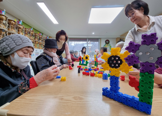 Older adults play with toy bricks at a nursing home that used to be a kindergarten in Gwangju on Jan. 3. The bricks were used by the former kindergarten students. [HWANG HEE-KYU]
