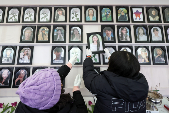 Family members of victims of the 2022 Itaewon disaster take down portraits of their loved ones ahead of a memorial march Wednesday. [NEWS1]