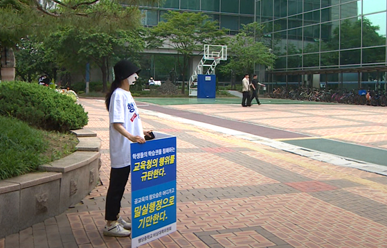 A person holds a placard that reads, "I denounce the education office's irresponsible action that ignores students' rights for study," in front of the Seoul Seongdong-Gwangjin District Office of Educational Support in Seongdong District, eastern Seoul in 2023. [SCREEN CAPTURE]
