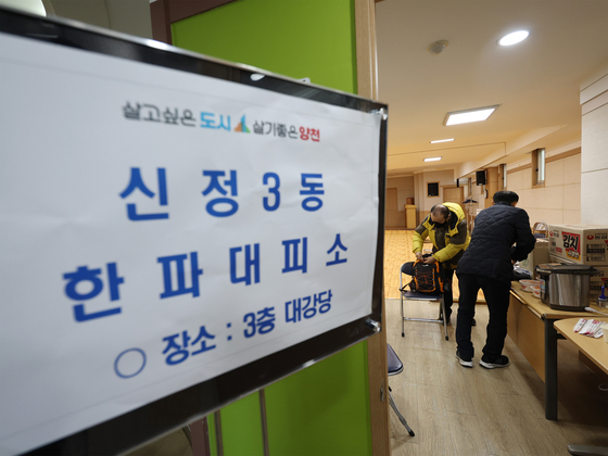 A resident in Yangcheon district, western Seoul, puts an instant hot pack in his backpack at an emergency service shelter inside the local community service center on Thursday after a valve malfunction of a pressurization system led to a shutdown in hot water supply and heating in the region. [YONHAP]