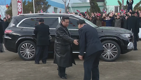 In this photograph released by Pyongyang's state-controlled Korean Central Television on Monday, North Korean leader Kim Jong-un is seen greeting an official shortly after getting out of a Mercedes-Benz Maybach GLS 600 sports utility vehicle. The rear right-side door bears the insignia of his position as president of the North's State Affairs Commission. [YONHAP]
