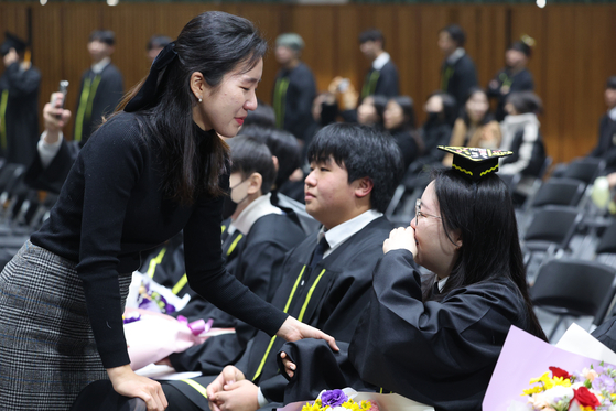 One of the last graduates of the special division of Duksoo High School in Seongdong District, eastern Seoul, cries with her teacher at a graduation ceremony this month. [YONHAP] 