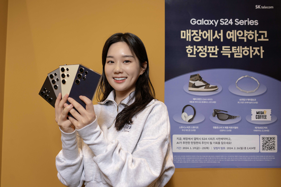 A model poses with the Galaxy S24 at an SK Telecom shop in front of a promotional poster for an upcoming giveaway. [SK TELECOM]