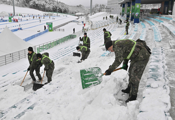 Soldiers clear snow from the stands ahead of the single mixed relay biathlon during the Gangwon Youth Olympics at Alpensia Biathlon Centre in Pyeongchang on Jan. 21. [AFP/YONHAP]