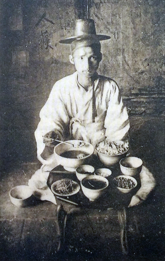 An image on a postcard made in Paris, France, of a Korean man sitting before a dining table with a huge rice bowl on it, during the late Joseon Dynasty (1392-1910) in the 1890s. [JOONGANG PHOTO/JOO YOUNG-HA]