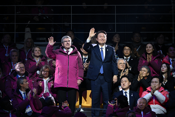 President Yoon Suk Yeol, right, and Thomas Bach, president of the International Olympic Committee, wave to the audience during the opening ceremony for the Winter Youth Olympics held at Gangneung Oval in Gangneung, Gangwon, on Friday. [PRESIDENTIAL OFFICE] 