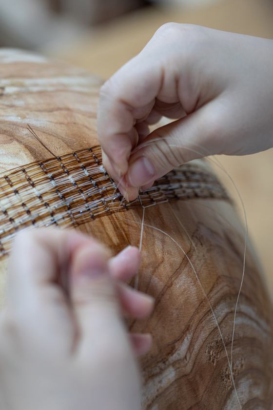 Jeong Da-hye works on her horsehair baskets at her studio inside her home in Seoul. [SOLUNA CRAFT]
