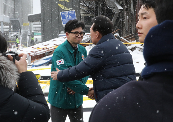 President Yoon Suk Yeol, right, greets People Power Party interim leader Han Dong-hoon during a visit to check on the site of a fire at a traditional market in Seocheon, South Chungcheong, on Tuesday. [JOINT PRESS CORPS]