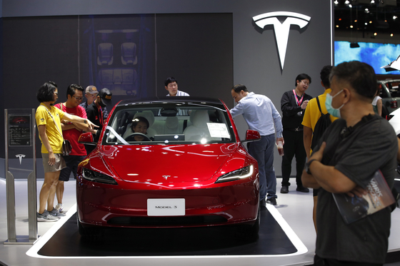 Visitors inspect a Tesla Model 3 electric car displayed at the 40th Thailand International Motor Expo 2023 in Bangkok, Thailand, on Dec. 4. [EPA/YONHAP]