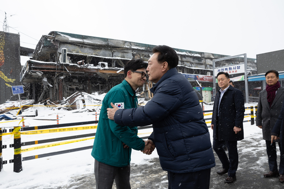 President Yoon Suk Yeol, right, greets People Power Party interim leader Han Dong-hoon during a visit to check on the site of a fire at a traditional market in Seocheon County, South Chungcheong, on Tuesday. [PRESIDENTIAL OFFICE] 