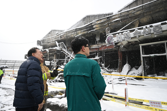 President Yoon Suk Yeol, left, and People Power Party interim leader Han Dong-hoon, right, are briefed on damages incurred by a fire at a traditional market for marine products in Seocheon County, South Chungcheong, on Tuesday. [PRESIDENTIAL OFFICE]