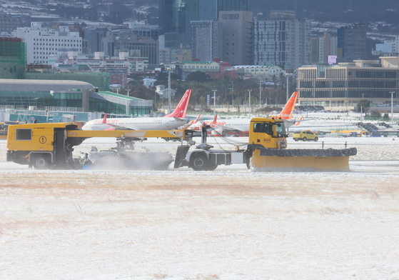 A snowplow clears the snow that fell on Jeju International Airport's runway on Tuesday. [YONHAP] 